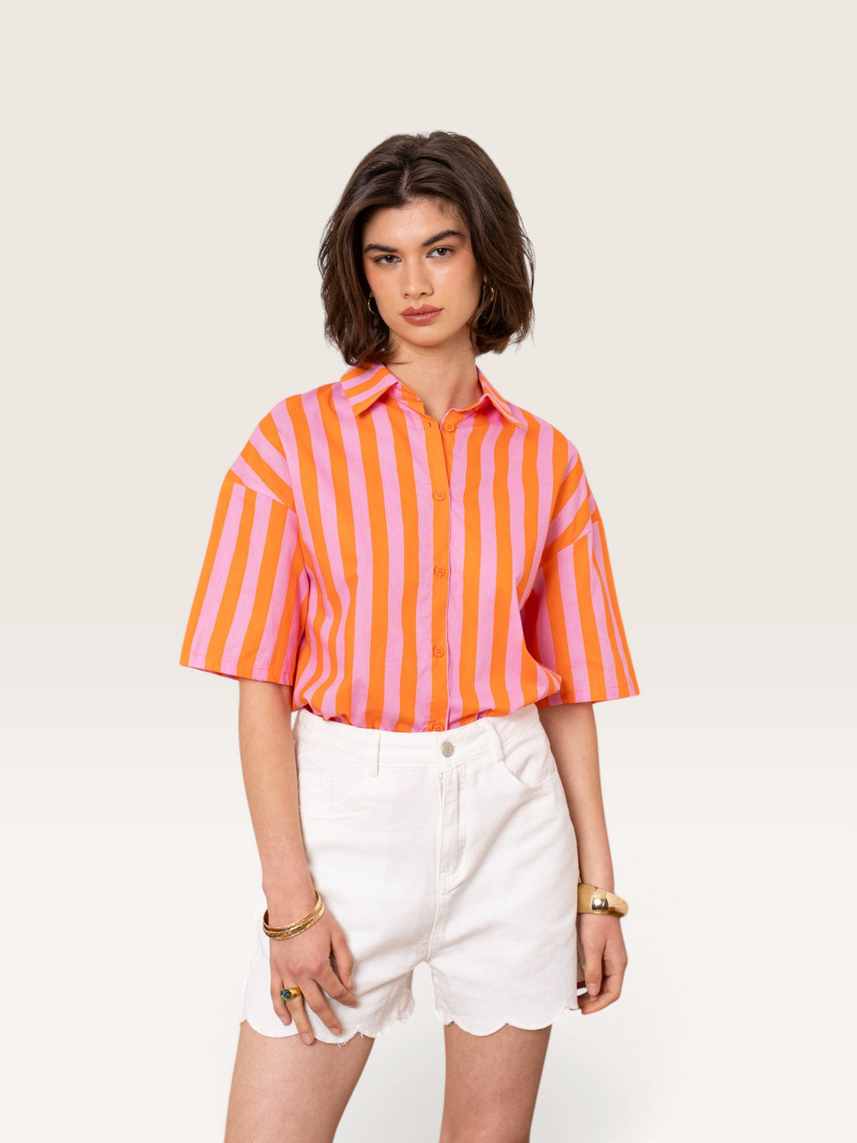Chemise rayée orange et rose en coton Sable_blanc_collection portée par une femme avec un short blanc