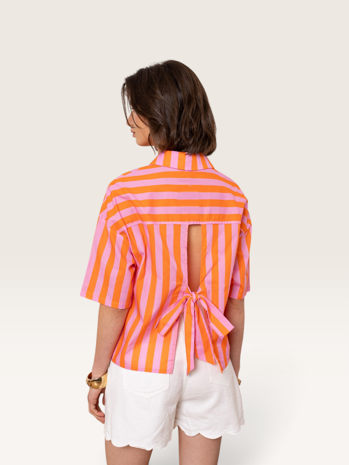 Chemise Sable_blanc_collection en coton rayé rose et orange avec dos ouvert et nœud décoratif porté par une femme