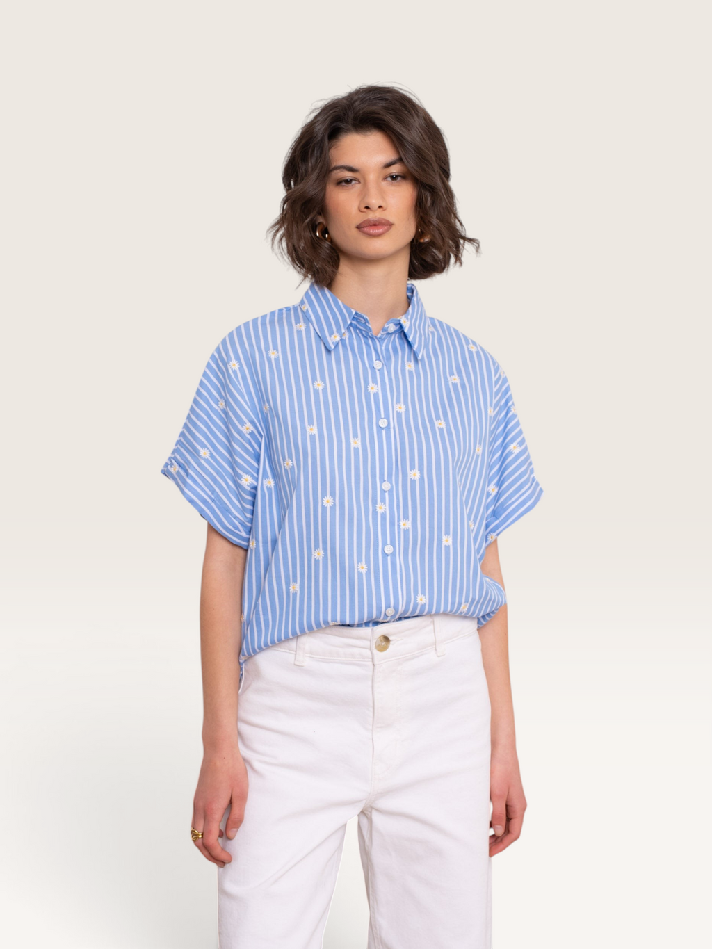 Femme portant une chemise Sable_blanc_collection bleue à rayures verticales et motifs de petites fleurs blanches