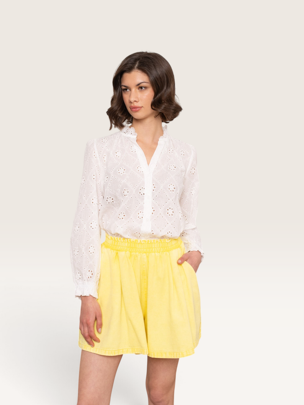 Modèle portant un chemisier blanc en coton brodé et un short jaune Sable_blanc_collection