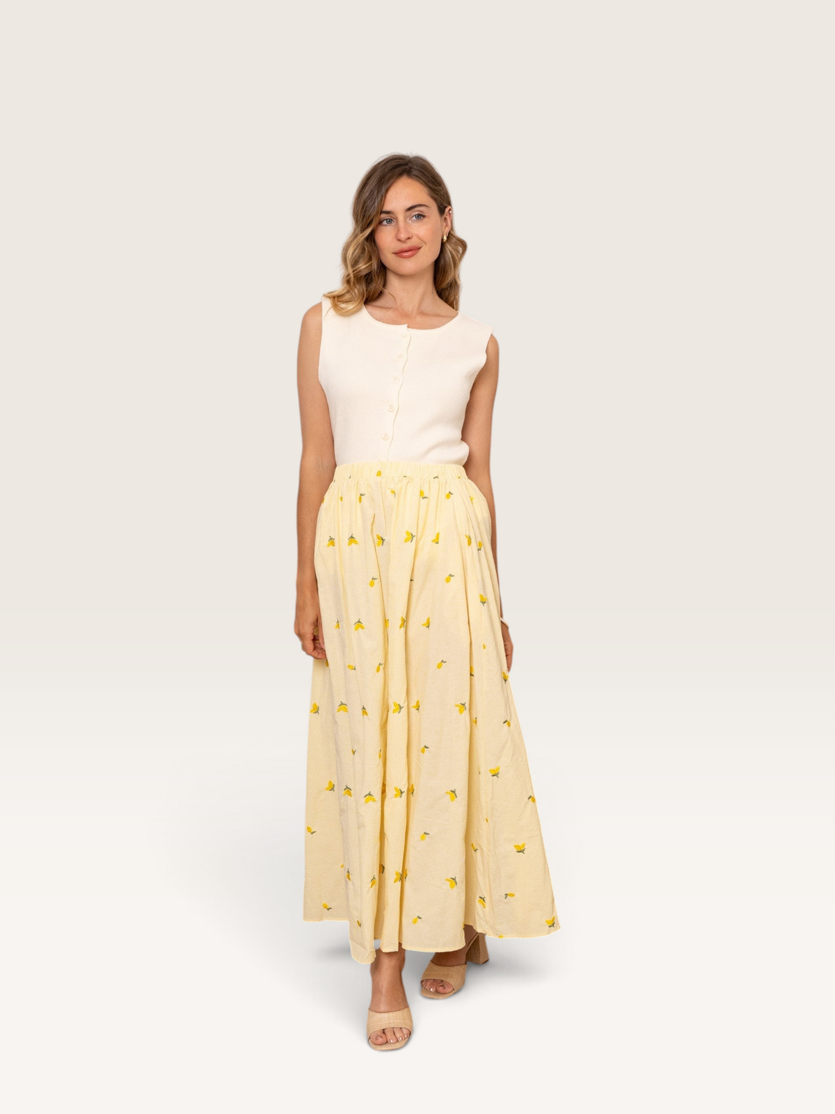 Femme portant une jupe longue Sable_blanc_collection en coton jaune à motifs citrons avec un haut sans manches