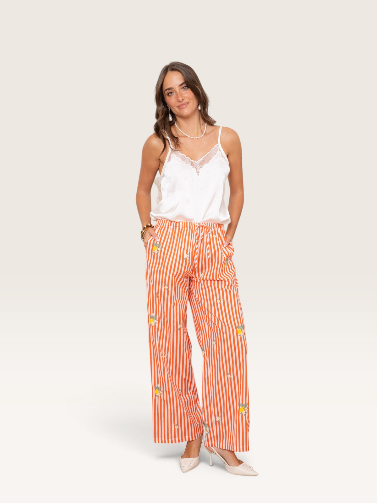 Femme portant le pantalon Kilky Sable_blanc_collection en coton rayé orange et blanc avec motifs floraux