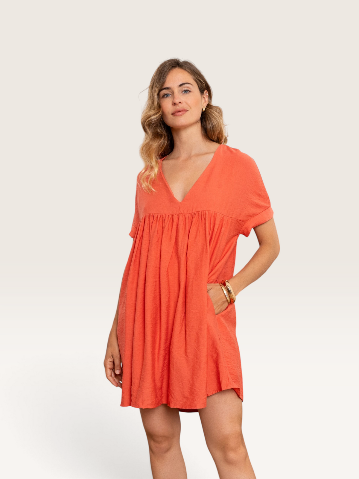 Femme portant une robe courte Sable_blanc_collection orange en coton avec col en V et poches latérales