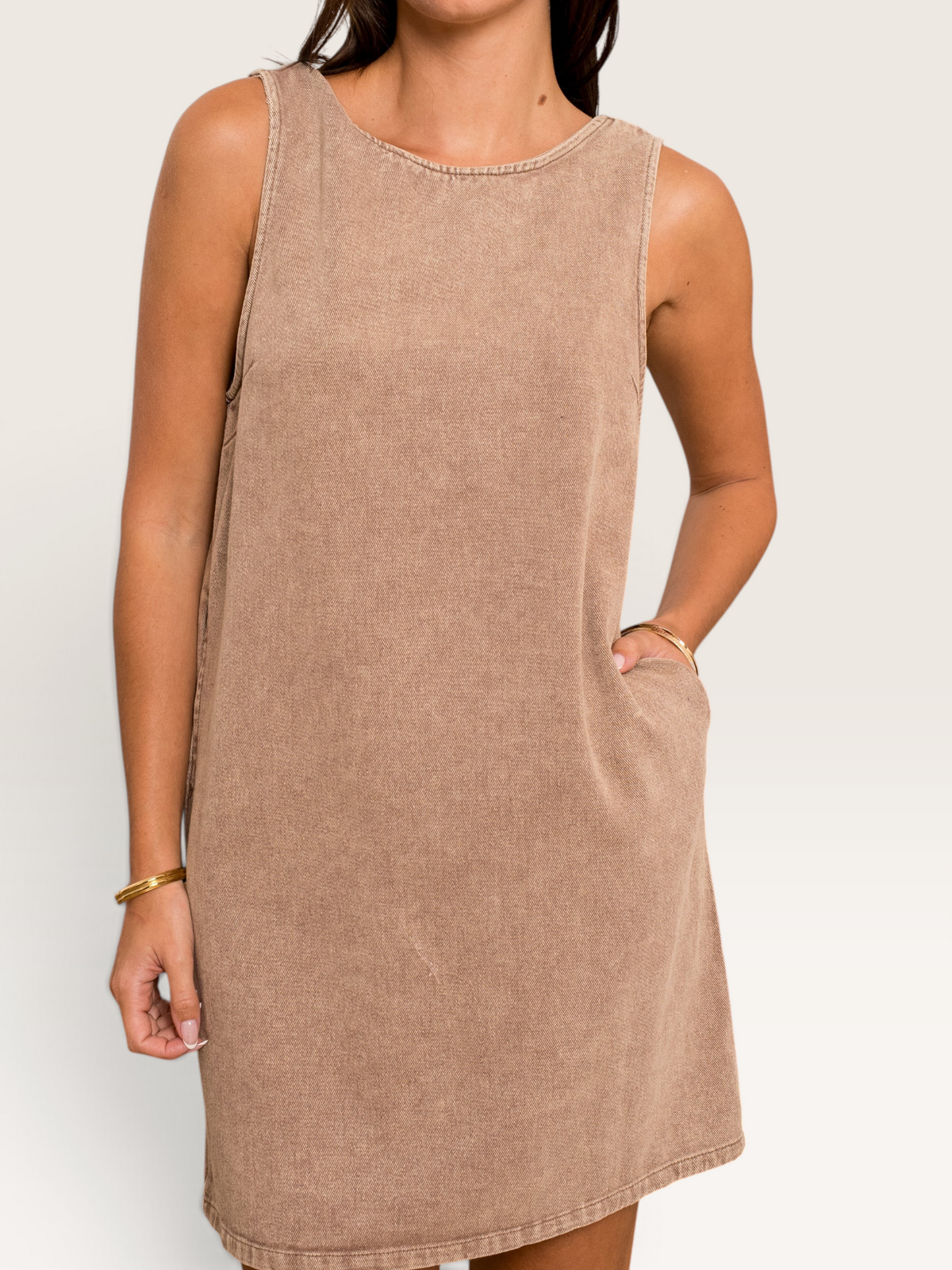 Robe courte sans manches Sable_blanc_collection en coton beige avec poches latérales sur une femme