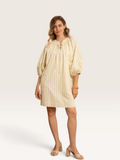 Femme portant la robe courte Sable_blanc_collection Kilky jaune à rayures fines, manches bouffantes et col noué