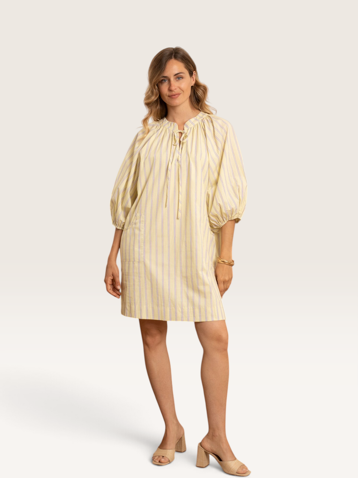 Femme portant la robe courte Sable_blanc_collection Kilky jaune à rayures fines, manches bouffantes et col noué