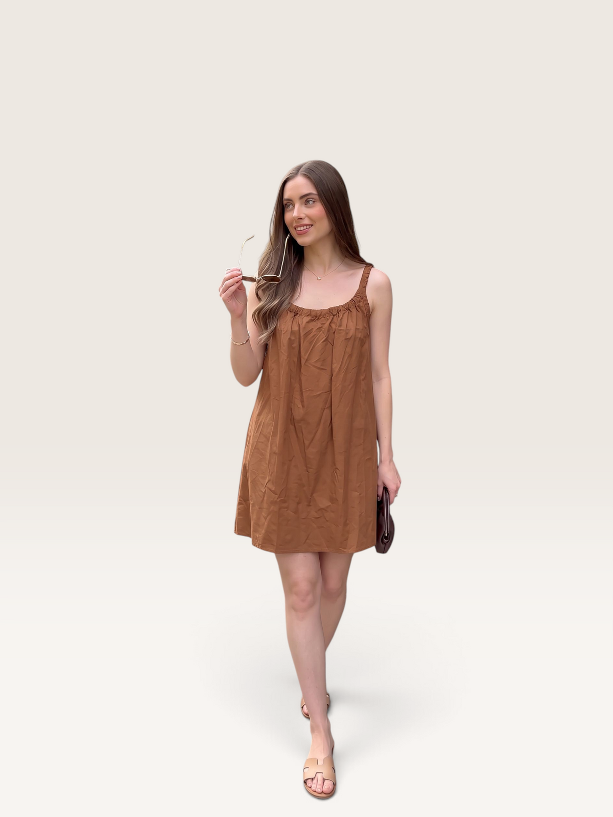 Robe courte Sable_blanc_collection en popeline de coton marron à bretelles, portée par une femme avec des lunettes.