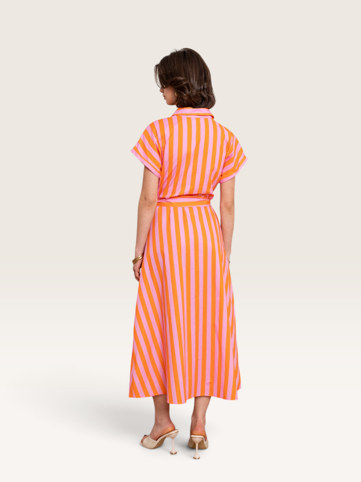 Vue arrière d'une femme portant une robe chemise Sable_blanc_collection rayée rose et orange en coton