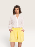 Modèle portant un short jaune Sable_blanc_collection en coton avec une chemise blanche brodée à manches longues