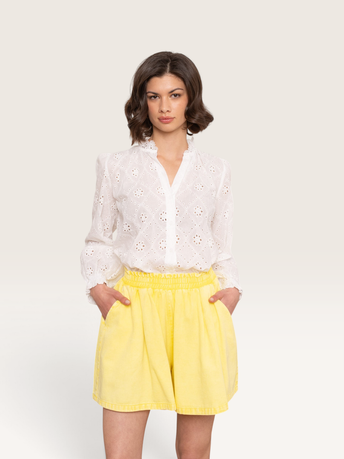 Modèle portant un short jaune Sable_blanc_collection en coton avec une chemise blanche brodée à manches longues