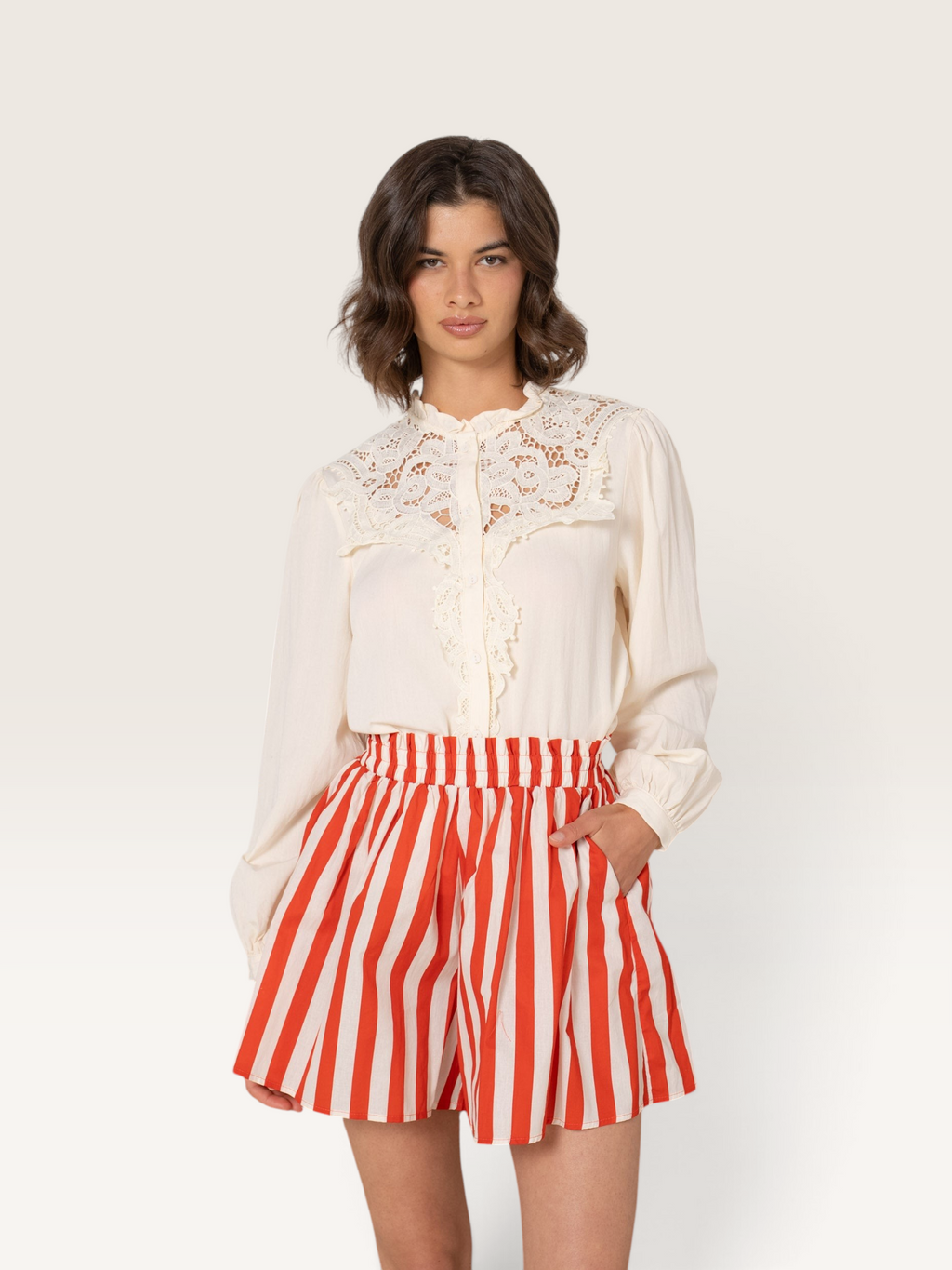 Femme portant un short rayé rouge et blanc Sable_blanc_collection avec une blouse en coton à détails en dentelle